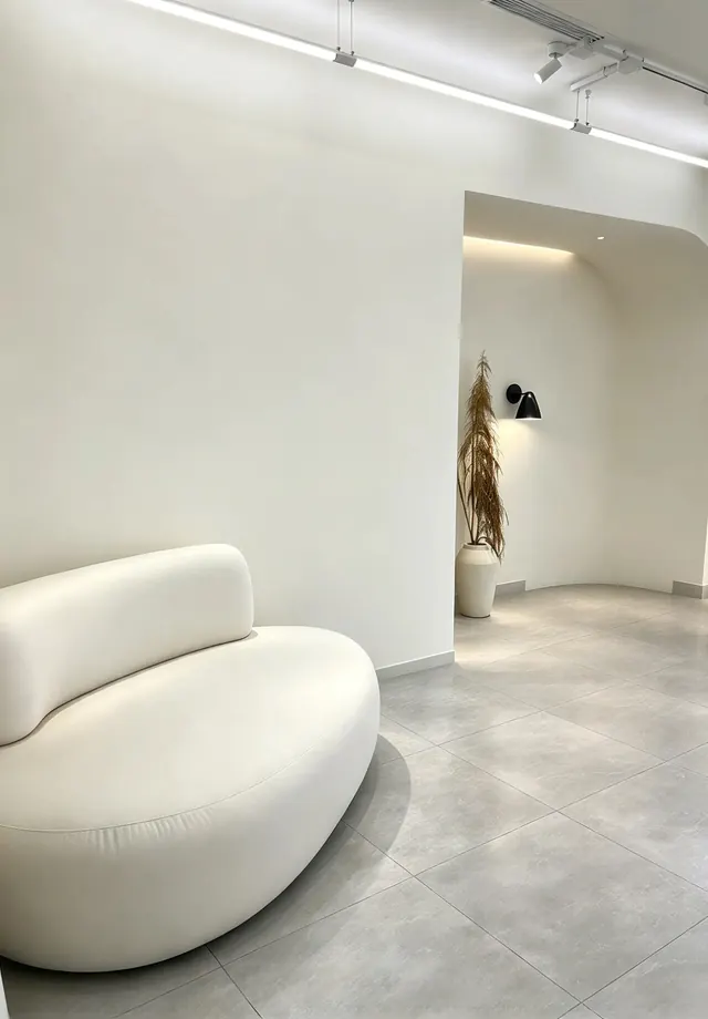 Ambiente branco com sofá curvo, arco e trilho de iluminação